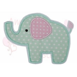 Könnte beinhalten: Ein Stoffaufnäher eines Cartoon-Elefanten. Der Elefant ist hellgrün mit weißen Sternmustern und einem rosa Ohr mit weißen Punkten. Der Aufnäher ist mit hellgrünen Nähten umrandet und hat einen kleinen Schwanz.