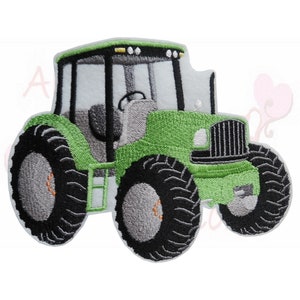 Könnte beinhalten: Gestickter Aufnäher eines grünen Traktors mit schwarzen Reifen. Der Traktor hat ein detailliertes Design, einschließlich Kabine, Scheinwerfern und Lenkrad. Der Aufnäher ist wahrscheinlich für Kleidung oder Accessoires.