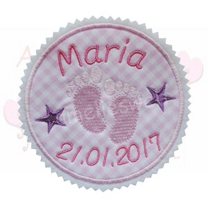 Könnte beinhalten: Ein runder Aufnäher mit rosa-weißem Vichy-Karo-Muster, bestickt mit dem Namen "Maria" in Rosa. Er zeigt Babyfüße, zwei lila Sterne und das Datum "21.01.2017". Der Aufnäher hat einen weißen, gezackten Rand.