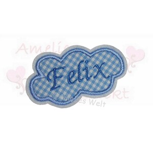 Könnte beinhalten: Ein blau-weiß kariertes wolkenförmiges Patch mit dem Namen "Felix" in blauer Schrift gestickt. Das Patch hat einen hellblauen Rand und eine weiße Rückseite. Das Patch ist wahrscheinlich für Kleidung oder Accessoires.