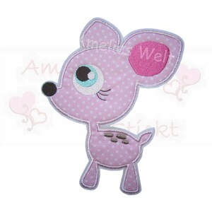 Könnte beinhalten: Ein rosa und weiß gepunkteter Hirsch-Applikation mit einem hellblauen Auge und einem rosa Ohr. Der Hirsch hat eine braune Nase und einen weißen Umriss. Der Text "Amelis Welt" ist auf dem Bild sichtbar.
