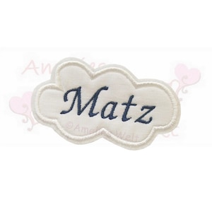 Könnte beinhalten: Ein weißer, wolkenförmiger Aufnäher mit dem Namen "Matz" in marineblauer Schreibschrift gestickt. Der Aufnäher hat einen weißen Rand und ist vor einem weißen Hintergrund platziert.