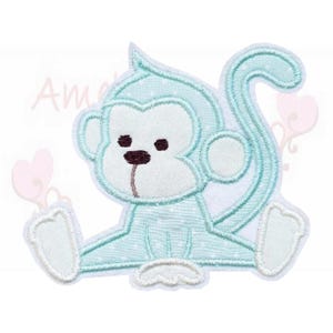 Könnte beinhalten: Hellblaues Affen-Applikation mit weißen Akzenten. Der Affe sitzt mit ausgestreckten Beinen und Schwanz. Die Applikation hat ein gepunktetes Muster auf dem Körper des Affen und ist mit hellblauem Faden bestickt. Das Wort "Am" ist in der oberen linken Ecke sichtbar.