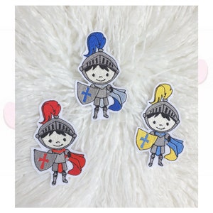 Könnte beinhalten: Drei gestickte Aufnäher von Cartoon-Rittern. Jeder Ritter trägt einen Helm und hält einen Schild mit einem Kreuz. Ein Ritter hat eine rote Feder und einen Umhang, ein anderer hat eine blaue Feder und einen Umhang, und der dritte hat eine gelbe Feder und einen blauen Umhang.