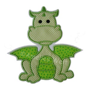 Könnte beinhalten: Ein grünes Drachen-Applikation mit einem Vichy-Körper und gepunkteten Flügeln. Der Drache hat schwarze Augen und sitzt. Der Text "© Amelies Weff" befindet sich auf den Flügeln.