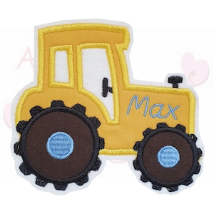 Könnte beinhalten: Gelb gestickter Traktoraufnäher mit braunen Rädern und dem Namen "Max" in blauer Schrift. Der Traktor hat ein weißes Fenster und ein schwarzes Lenkrad. Der Aufnäher ist weiß umrandet.