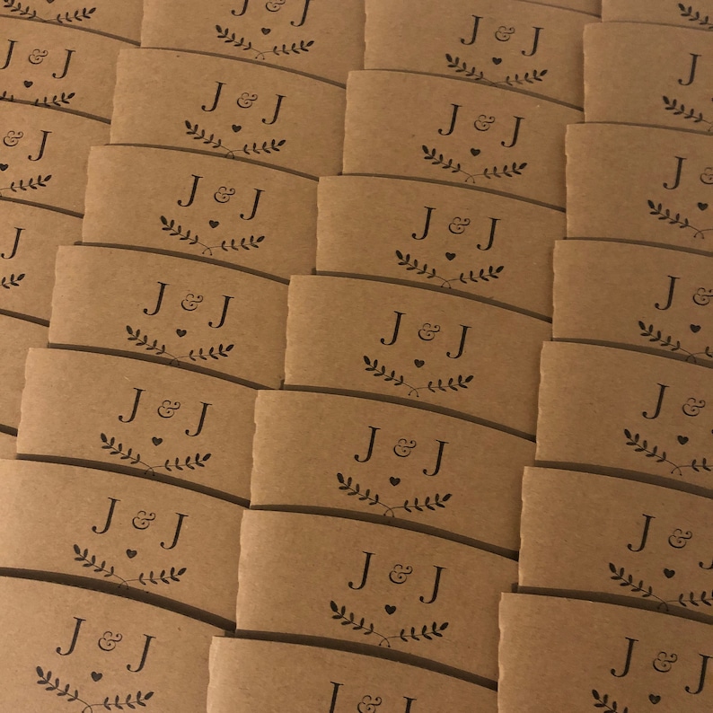 May include: A stack of brown paper coffee cup sleeves with the initials "J&J" and a small heart printed on each sleeve.
