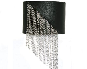 Könnte beinhalten: Schwarzes Lederarmband mit einem Fransenbesatz aus silbernen Ketten. Die Fransen hängen in einer diagonalen Form herunter.