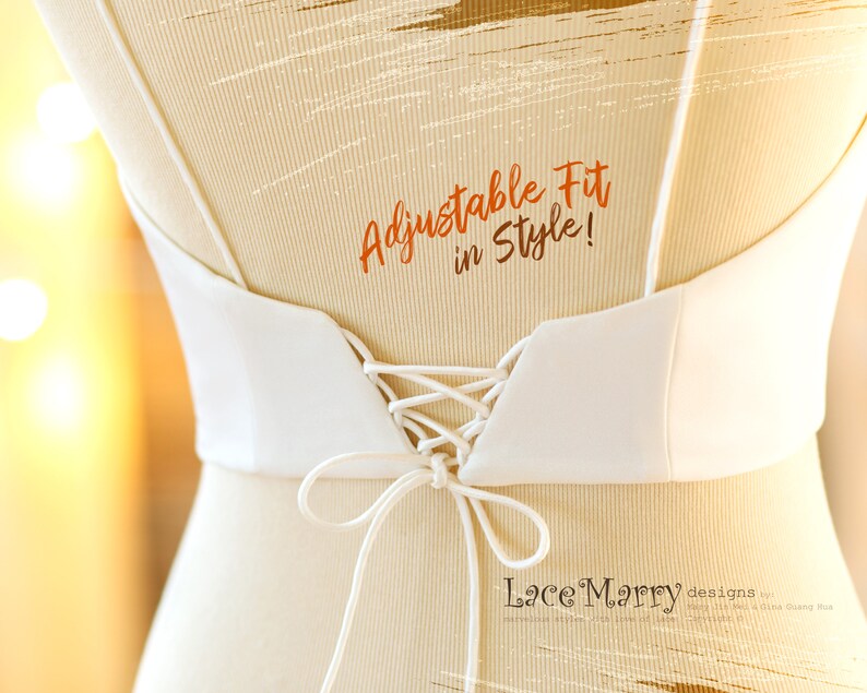 Pu&ograve; includere: Un corpetto da sposa bianco con schienale a lacci. Il corpetto ha una scollatura a V ed &egrave; regolabile. Il testo "Adjustable Fit in Style!" &egrave; scritto in arancione sul retro del corpetto. Il testo "LaceMarry designs by" &egrave; scritto in nero nella parte inferiore dell'immagine.