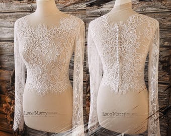 May include: A white lace bridal top with long sleeves and a button closure down the back. The top is made of delicate lace with a floral pattern. "Lace Marry designs" is printed on the bottom of the image.