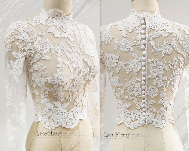 May include: A white lace top with long sleeves and a high neckline. The intricate floral lace design covers the entire top, with a row of buttons down the back. The top is displayed on a mannequin.