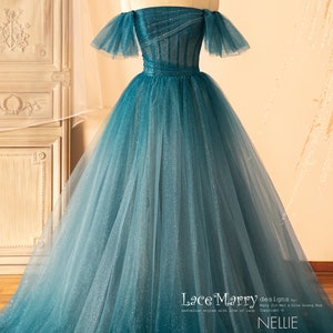 K&ouml;nnte beinhalten: Ein t&uuml;rkisfarbenes T&uuml;ll-Ballkleid mit einem herzf&ouml;rmigen Ausschnitt und abfallenden, schulterfreien &Auml;rmeln. Das Kleid ist mit Pailletten verziert und hat ein tailliertes Oberteil. Der Rock ist voll und flie&szlig;end. Das Kleid wurde von Lace Marry entworfen und hei&szlig;t "Nellie".