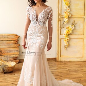 May include: A fitted, ivory wedding dress with a sheer bodice and long sleeves. The dress features intricate floral lace detailing and a flowing train.