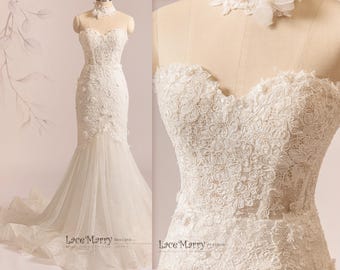 May include: A white lace wedding dress with a sweetheart neckline and a fitted bodice. The skirt is made of tulle and has a mermaid silhouette. The dress features delicate floral lace appliques and a sheer illusion neckline.