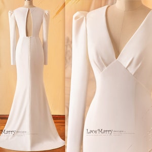 May include: A white long-sleeved wedding dress with a fitted bodice, a V-neckline, and a low back. The dress has a fitted silhouette and a flowing skirt. The dress is shown from the front and back.