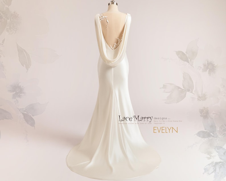 Pu&ograve; includere: Un abito da sposa in satin bianco con schiena scoperta e scollatura a cascata drappeggiata. L'abito presenta delicati dettagli in pizzo sul retro e uno strascico.