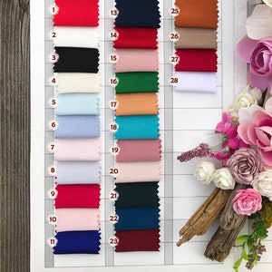 Pu&ograve; includere: Cartella colori per tessuto in cr&ecirc;pe elastico. La cartella mostra 28 colori diversi, tra cui rosso, avorio, nero, avorio scuro, azzurro, rosa chiaro, blu scuro, rosso scuro, nudo, blu navy, bordeaux e bianco. La cartella &egrave; numerata da 1 a 28.