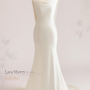 Pu&ograve; includere: Un abito da sposa in satin bianco con scollo a barchetta e silhouette aderente. L'abito ha una lunga coda ed &egrave; stato disegnato da Lace Marry designs by Mary J. Wei & Diana Shang Hua. Il testo "EVELYN" &egrave; visibile sull'abito.