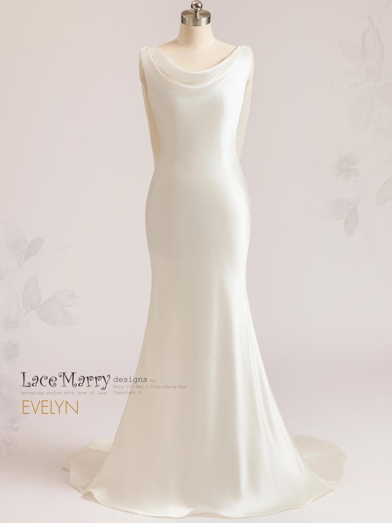 Pu&ograve; includere: Un abito da sposa in satin bianco con scollo a barchetta e silhouette aderente. L'abito ha una lunga coda ed &egrave; stato disegnato da Lace Marry designs by Mary J. Wei & Diana Shang Hua. Il testo "EVELYN" &egrave; visibile sull'abito.
