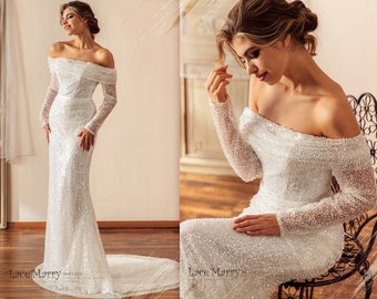 Op de afbeelding: Een witte off-shoulder bruidsjurk met lange mouwen en een aansluitende pasvorm. De jurk is bedekt met pailletten en heeft een sleep.