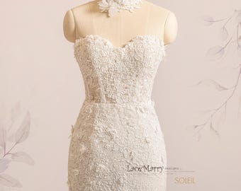 May include: A white strapless wedding dress with a fitted bodice and a skirt covered in delicate floral lace. The dress features a high neckline with a white lace choker.