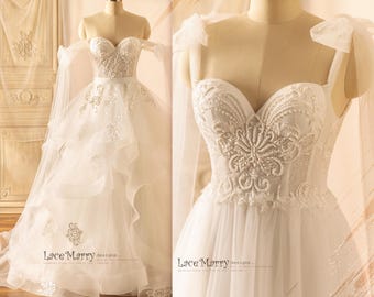 May include: A white wedding dress with a sweetheart neckline and a tulle skirt. The dress has a lace bodice with beaded embellishments and a detachable train. The dress is shown on a mannequin.