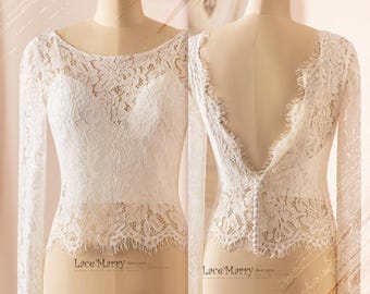 May include: White lace bridal top with long sleeves and a low back. The top has a scoop neckline and a button closure at the back.