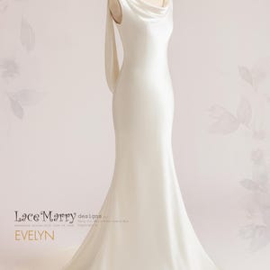 Pu&ograve; includere: Un abito da sposa in raso bianco con scollo a barca e una lunga coda. L'abito ha un design semplice ed elegante, perfetto per una sposa moderna.