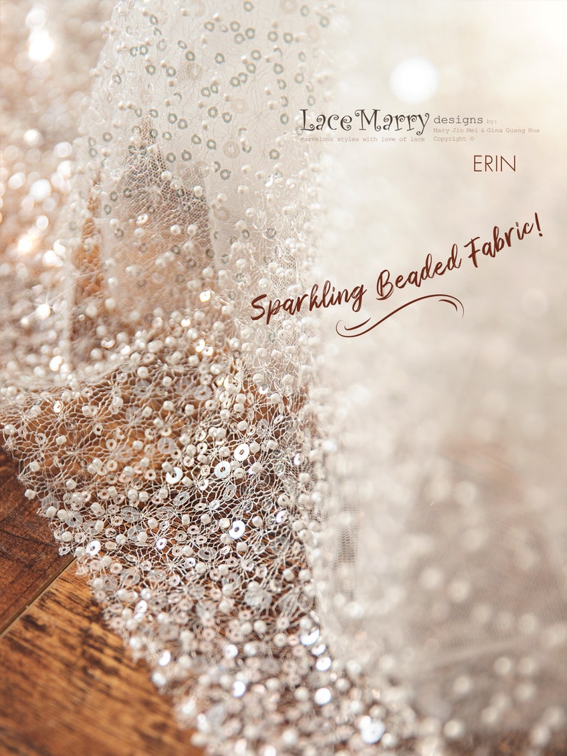 May include: Close-up of a white beaded fabric with a delicate lace pattern. The fabric is shimmering and has a subtle sparkle. The text "Lace Marry designs" and "Sparkling Beaded Fabric!" is visible in the image.
