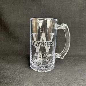 May include: A clear glass beer stein with a handle. The stein is engraved with the letter "W" and the name "Wagner" above the text "Best Man".