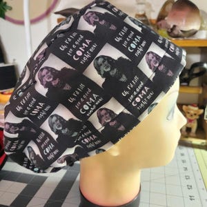 Peut inclure: Une charlotte de bloc opératoire noire et blanche avec un motif répétitif représentant une femme aux cheveux foncés et le texte "Oh, I'd kill for a good COMA right now" imprimé en caractères gras. Le tissu est froncé sur le dessus.