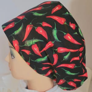 Peut inclure: Une charlotte chirurgicale noire ornée d'un motif répétitif de piments rouges et verts vifs. Le couvre-chef présente une forme arrondie et ajustée qui épouse la tête, mettant en valeur une variété de tailles et d'orientations de piments.