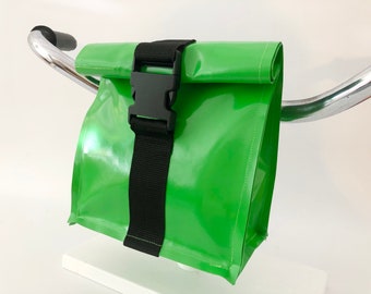 May include: A bright green waterproof bag with a black strap and buckle. The bag is attached to a silver handlebar.