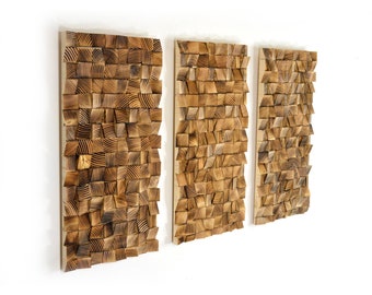May include: Three rectangular wooden wall art pieces with a geometric pattern of squares and rectangles. The wood is a light brown color with a darker brown stain.