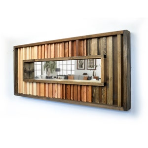May include: A rectangular wooden mirror with a unique design featuring a variety of wood tones and a rectangular mirror inset. The mirror is framed with a thick wooden border.