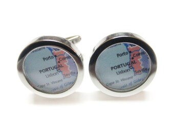 May include: A pair of silver cufflinks with a map of Portugal inside. The map shows the cities of Porto, Lisbon, and Seville.