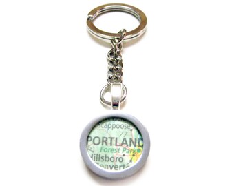 Puede incluir: Llavero de plata con un dije redondo con marco plateado que muestra un mapa de Portland, Oregón. El mapa muestra el texto "PORTLAND" y los nombres de las ciudades cercanas, incluyendo "Forest Park", "Hillsboro" y "Beaverton".