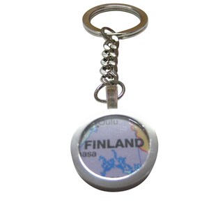 May include: A silver keychain with a round, silver-framed charm featuring a map of Finland with the word "FINLAND" printed in black.