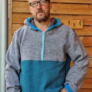 May include: A gray and teal hooded sweatshirt with a zipper closure. The sweatshirt has a contrasting teal panel on the lower half and a teal zipper.