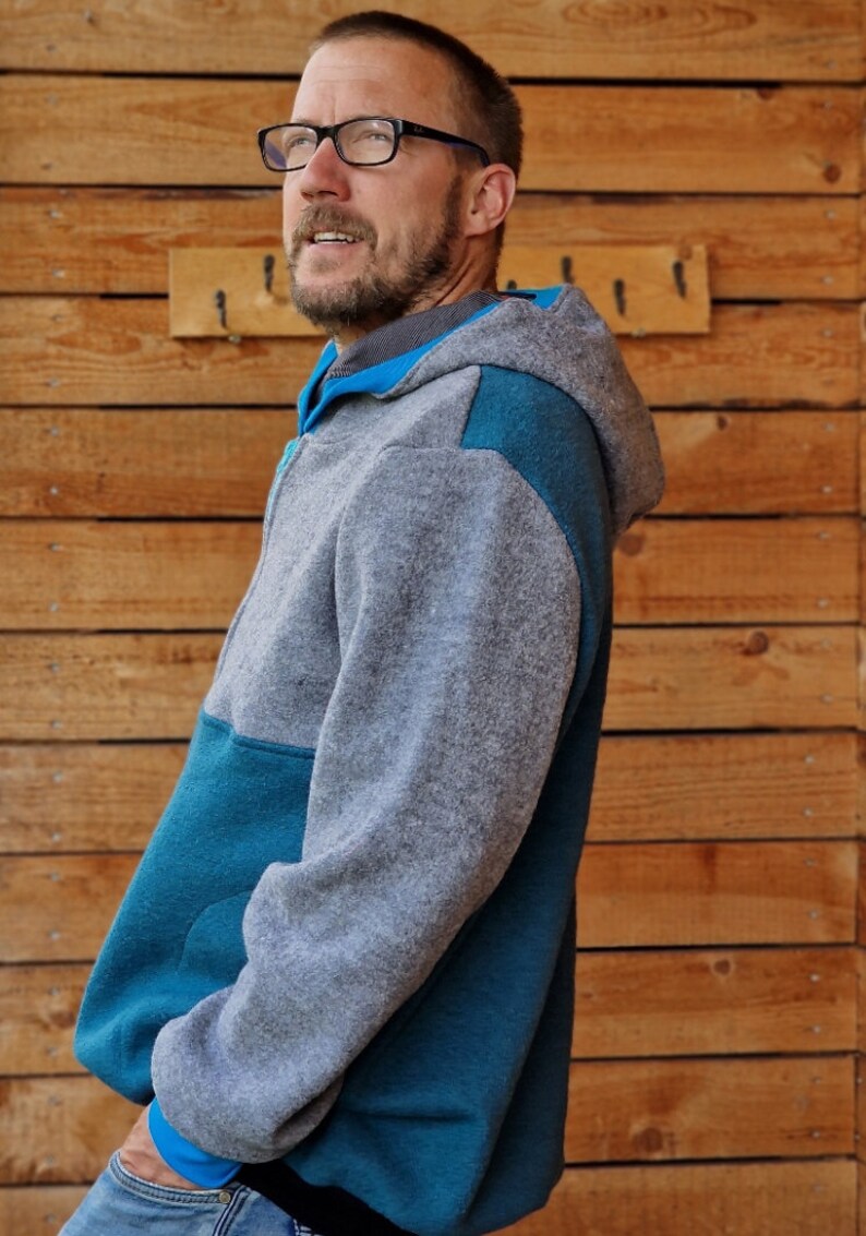 May include: A gray and teal hooded sweatshirt with a zipper closure. The sweatshirt has a contrasting teal panel on the left side and a teal panel on the right shoulder.