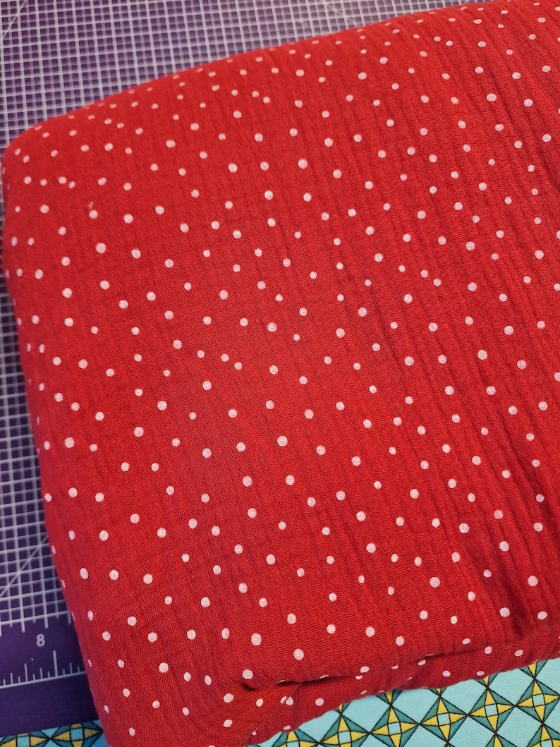 Pu&ograve; includere: Tessuto rosso con pois bianchi. Il tessuto ha un aspetto testurizzato e stropicciato.