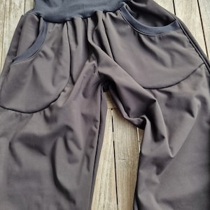 May include: Black trousers with a wide waistband and two large pockets on the front. The trousers are made of a soft, stretchy fabric.