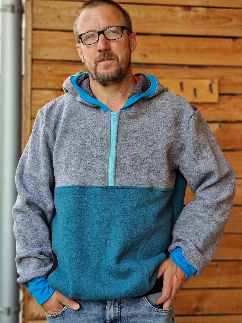 May include: A gray and teal hooded sweatshirt with a zipper closure. The sweatshirt has a contrasting teal panel on the lower half and a teal zipper.