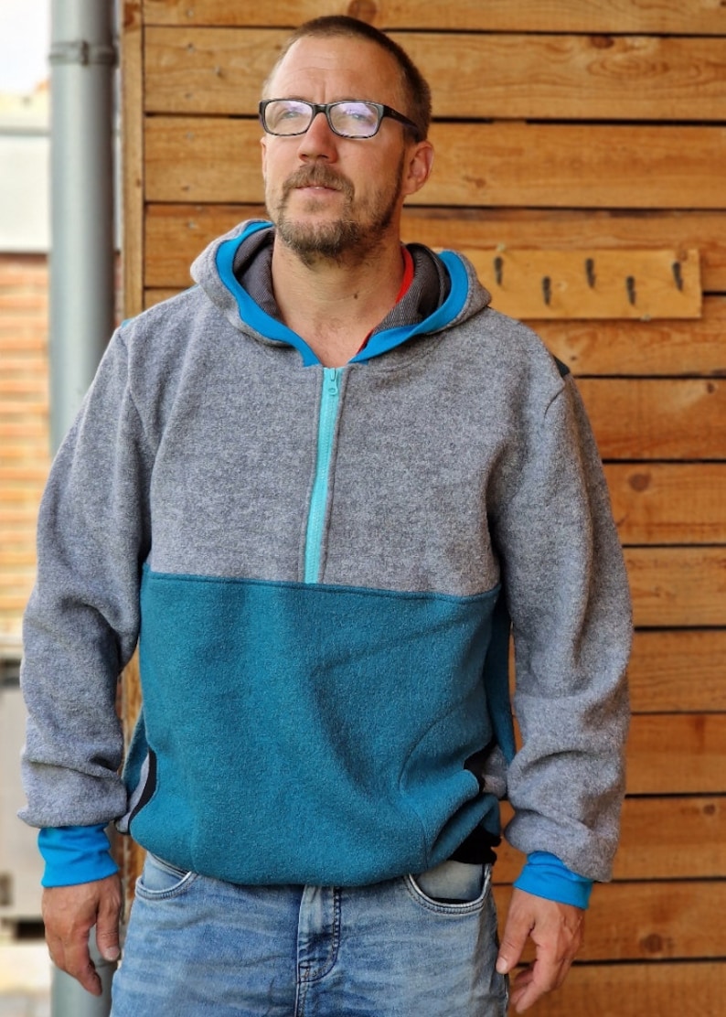 May include: A gray and teal hooded sweatshirt with a zipper closure. The sweatshirt has a contrasting teal panel on the lower half and teal zipper trim.