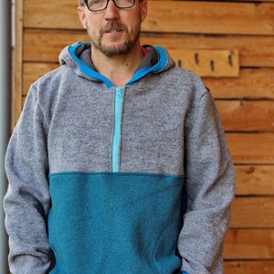 May include: A gray and teal fleece pullover with a half-zip closure. The zipper is teal and the hoodie has a gray hood.