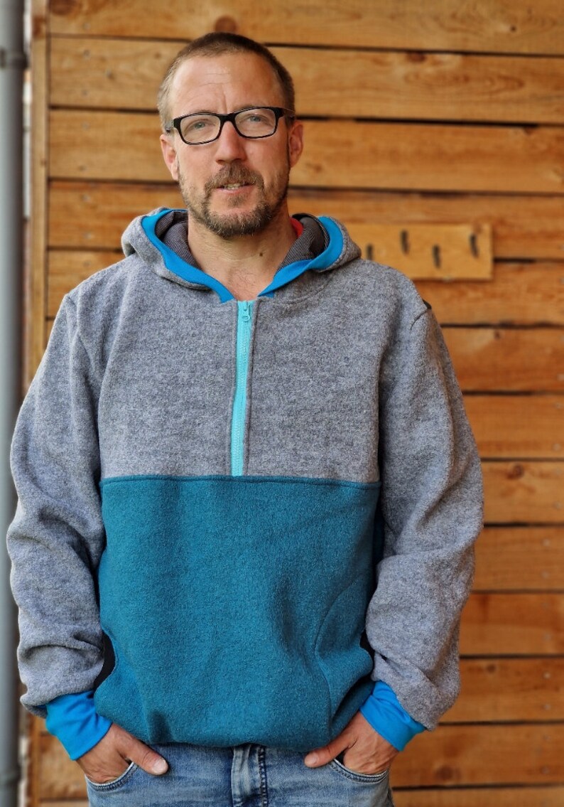 May include: A gray and teal fleece pullover with a half-zip closure. The zipper is teal and the hoodie has a gray hood.