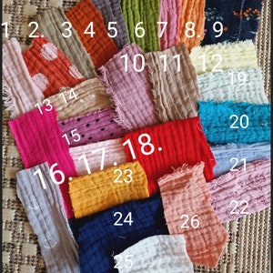 Pu&ograve; includere: Una collezione di 26 campioni di tessuto in vari colori e motivi, tra cui colori solidi, pois e stampe floreali. I campioni sono numerati da 1 a 26.