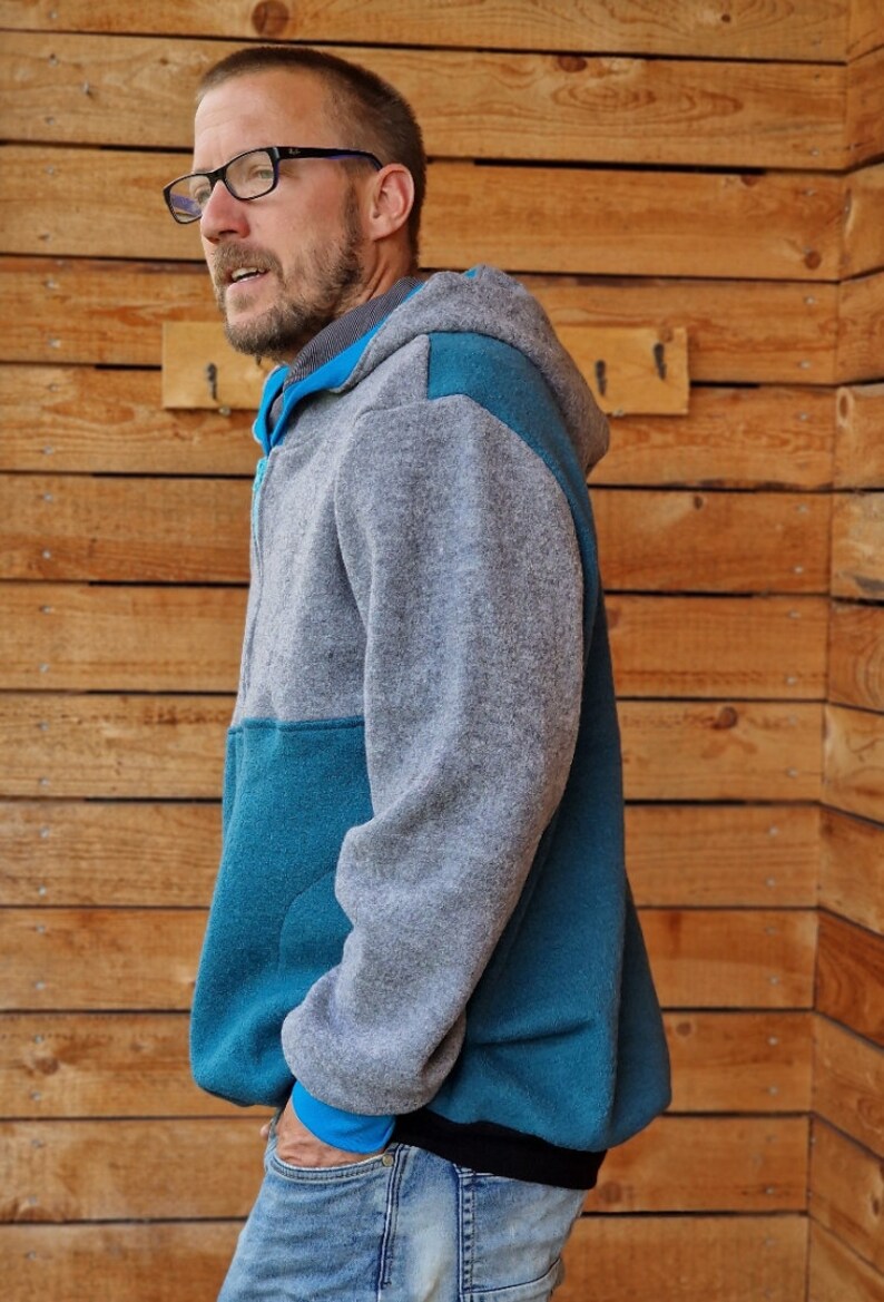 May include: A gray and teal hooded sweatshirt with a zipper closure. The sweatshirt has a contrasting teal panel on the front and sleeves.