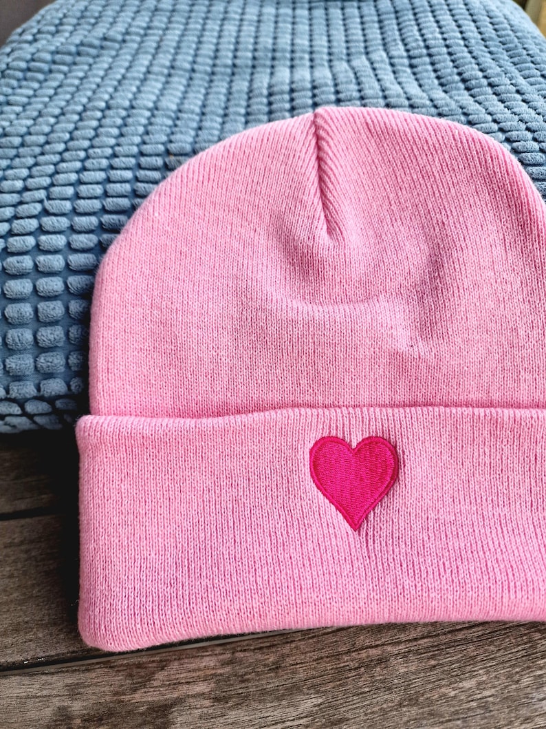 May include: Pink knit beanie with a red heart embroidered on the front.