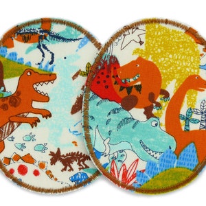 May include: Two round fabric patches with a dinosaur theme. One patch features a brown dinosaur with green and blue accents. The other patch features a blue dinosaur with orange and yellow accents.